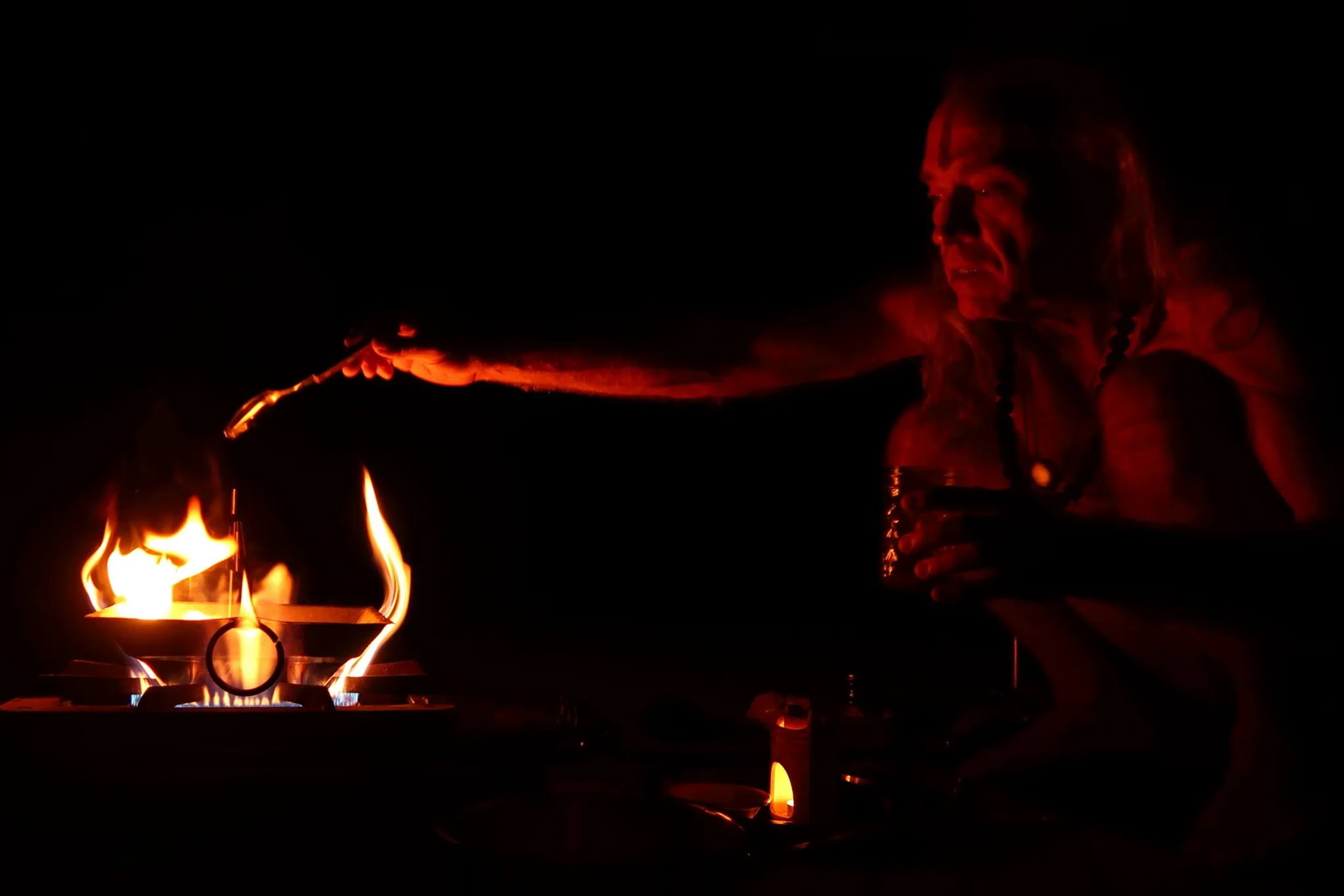 Kapilnath pouring ghee from a spoon onto a dhuni with fire.