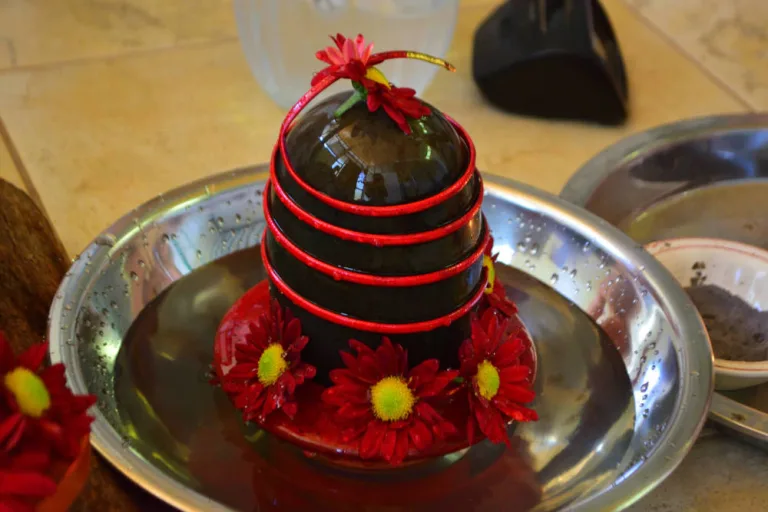 Stone lingam in bowl of water and flowers